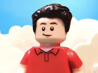 Lego figure with black hair, red shirt, smiling against a blue sky and white cloud backdrop. Playful and cheerful atmosphere.