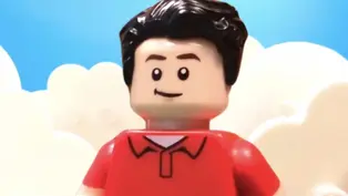 Lego figure with black hair, red shirt, smiling against a blue sky and white cloud backdrop. Playful and cheerful atmosphere.