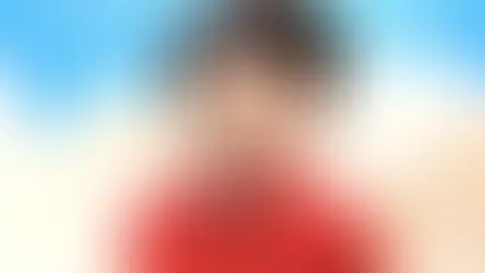 Lego figure with black hair, red shirt, smiling against a blue sky and white cloud backdrop. Playful and cheerful atmosphere.