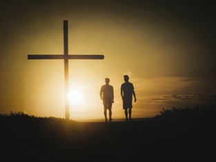 Silhouetted against a golden sunset, two people walk near a large cross on a hilltop, creating a serene and reflective scene.