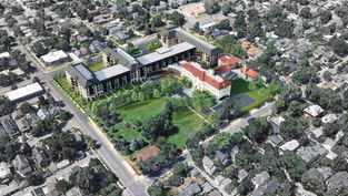 Aerial view of a large complex with modern and historic buildings surrounded by trees in a suburban neighborhood. Roads and houses visible nearby.