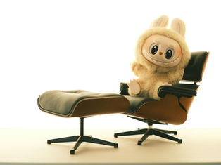 Cute plush toy with rabbit ears, smiling on a black leather chair with a matching footrest. Minimalist white background.