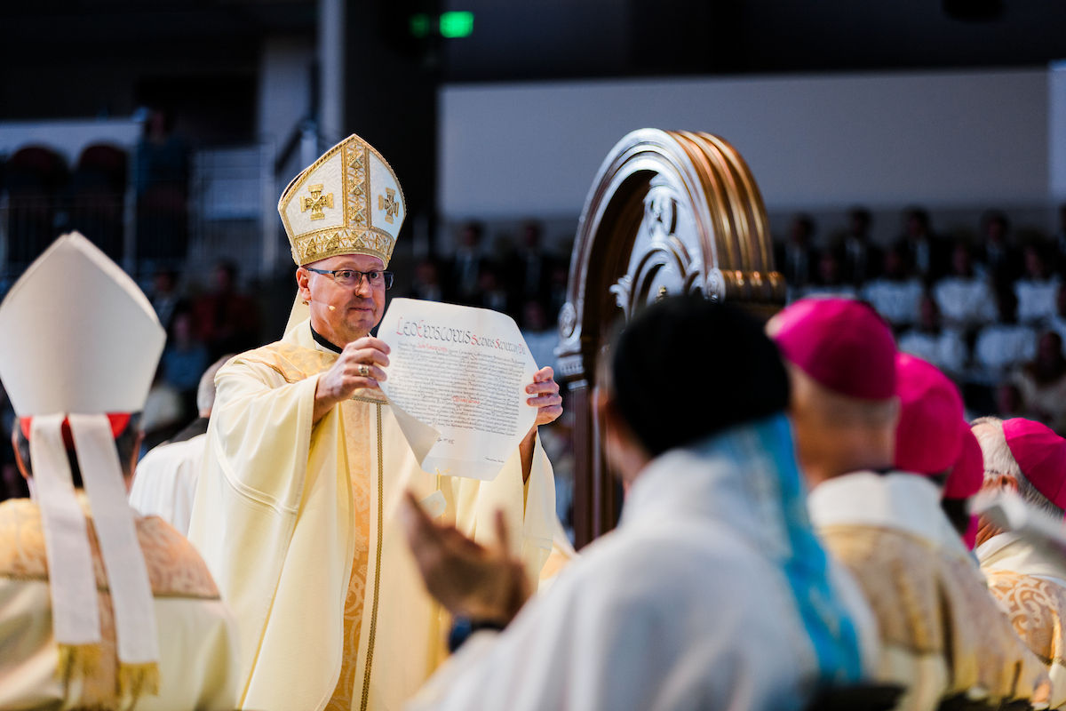The bishop presents an official document to the assembly during the installation ceremony.