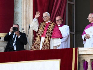 A man in ornate religious attire waves from a balcony, flanked by clerics in white and purple. A photographer captures the moment.