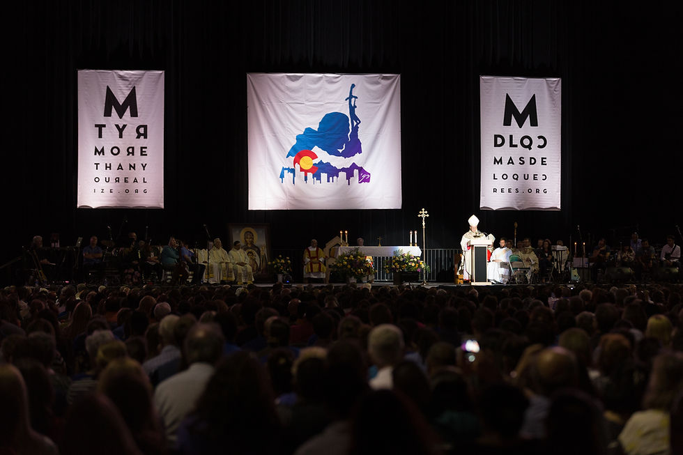 Crowded religious event with a speaker at a podium on stage. Banners with text in background. Attendees seated, focused, and attentive.