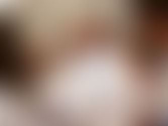 People in white gowns hold lit candles in a solemn ceremony. The setting is bright and blurred, evoking a peaceful, reverent mood.