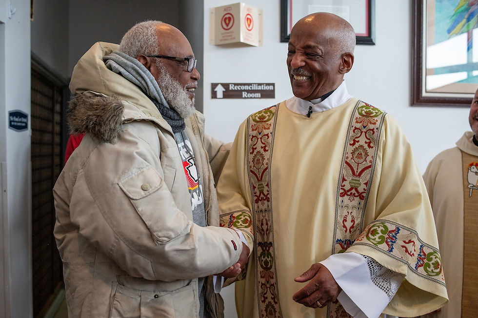 Two men warmly shake hands; one in a beige parka, the other in ornate religious robes. A "Reconciliation Room" sign is visible.