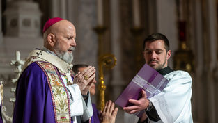 Clergyman in ornate purple and gold vestments prays beside another man holding a book in a church, solemn atmosphere, detailed carvings.