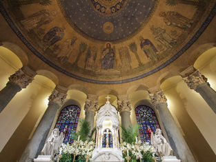 Ornate church interior with murals of biblical figures, stained glass windows, and a central altar adorned with lilies, evoking a serene mood.