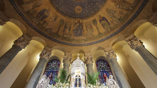 Ornate church interior with murals of biblical figures, stained glass windows, and a central altar adorned with lilies, evoking a serene mood.