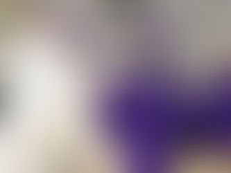 Priest gives communion to a student in purple graduation gown during a ceremony in a gym with banners and a tiger mural.