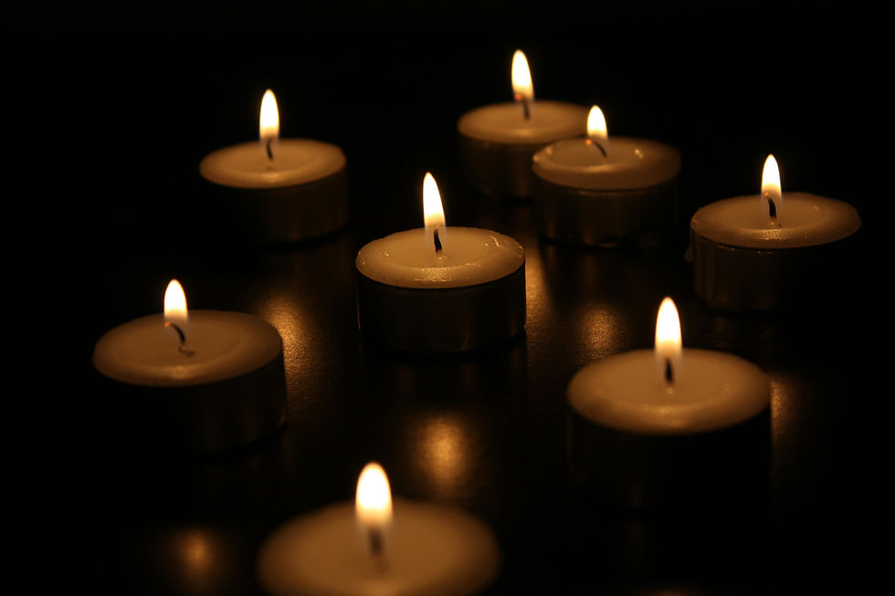 Eight lit tealight candles in a dark setting, creating a warm, serene glow with soft reflections on the surface.