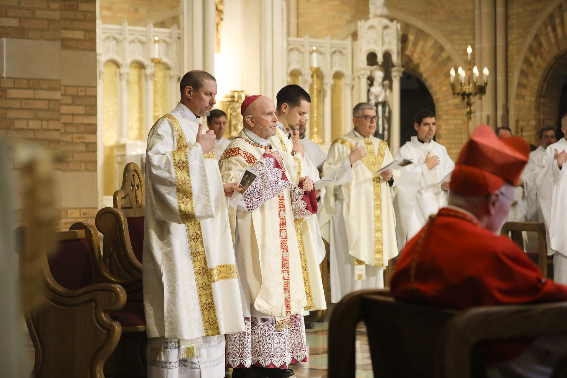 An archbishop prays during a religious ceremony in an ornate brick chapel. The mood is celebratory.