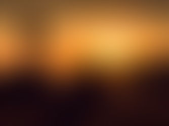 Silhouette of person sitting near a cross, gazing at a vibrant orange sunset over hills, creating a serene and contemplative mood.