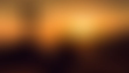 Silhouette of person sitting near a cross, gazing at a vibrant orange sunset over hills, creating a serene and contemplative mood.