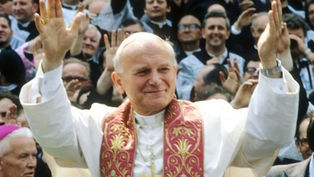 Cleric in white robe with ornate red stole raises hands, smiling. Crowd in background gestures with joy. Bright, joyful scene.