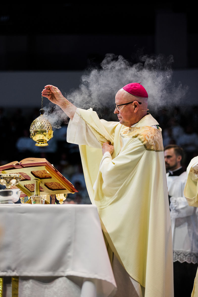 A bishop incenses the altar as smoke rises during the Eucharistic celebration.