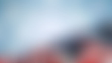 Folded American flag with stars and red-white stripes against a soft blue background with glowing star shapes
