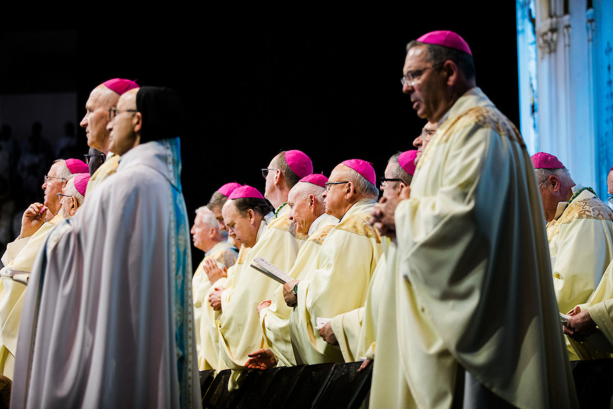 Bishops and clergy stand in prayer during the Mass.