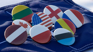 Flag pins arranged on a blue fabric backdrop. Bright colors feature flags of several countries, creating a sense of unity and diversity.