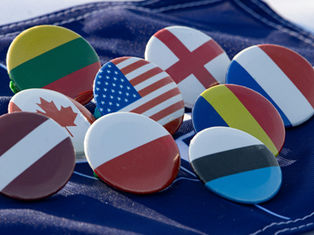 Flag pins arranged on a blue fabric backdrop. Bright colors feature flags of several countries, creating a sense of unity and diversity.