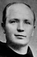 Black-and-white portrait of a serious man with a receding hairline, looking at the camera against a plain background.