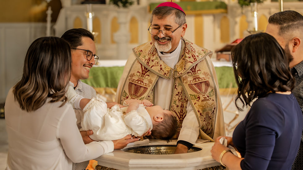 Priest smiling over a baby held by family during a church baptism, with ornate vestments and a warm, joyful atmosphere
