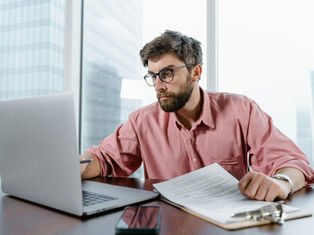 A businessman hunches over his computer, looking stressed, as he works on a project.