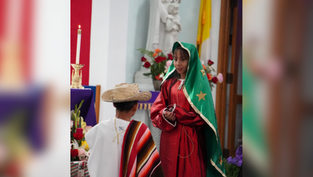 Children in traditional attire perform in a church. Girl in green and red, boy in sombrero. Candles, flowers, and statue in the background.