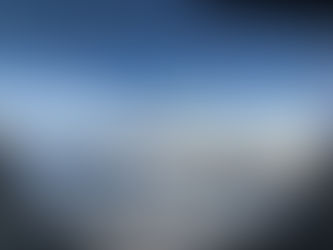 Airplane wing seen from a window above white clouds and mountains under a clear blue sky, calm and expansive view