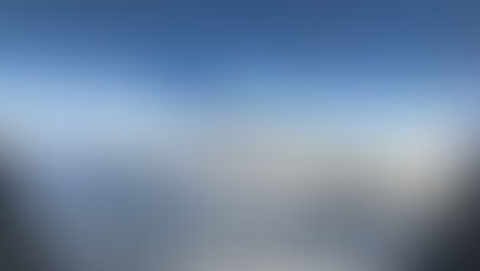 Airplane wing seen from a window above white clouds and mountains under a clear blue sky, calm and expansive view
