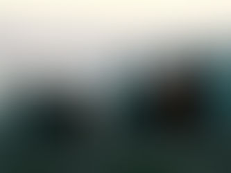Five people sit on a hill overlooking a misty valley at dusk. One wears a "247" shirt. City lights twinkle below, creating a tranquil mood.