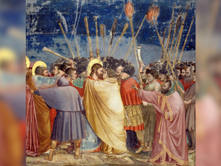 A dramatic scene with a group of people holding torches. A man in a golden robe is embraced. The night sky is in the background.