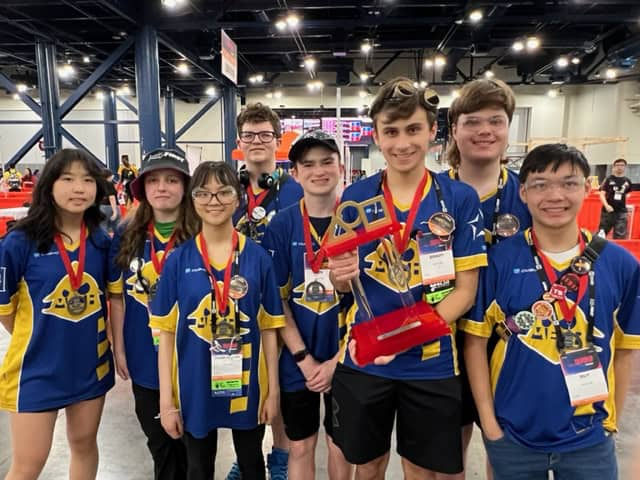 High school robotics team students holding an award after winning a championship.