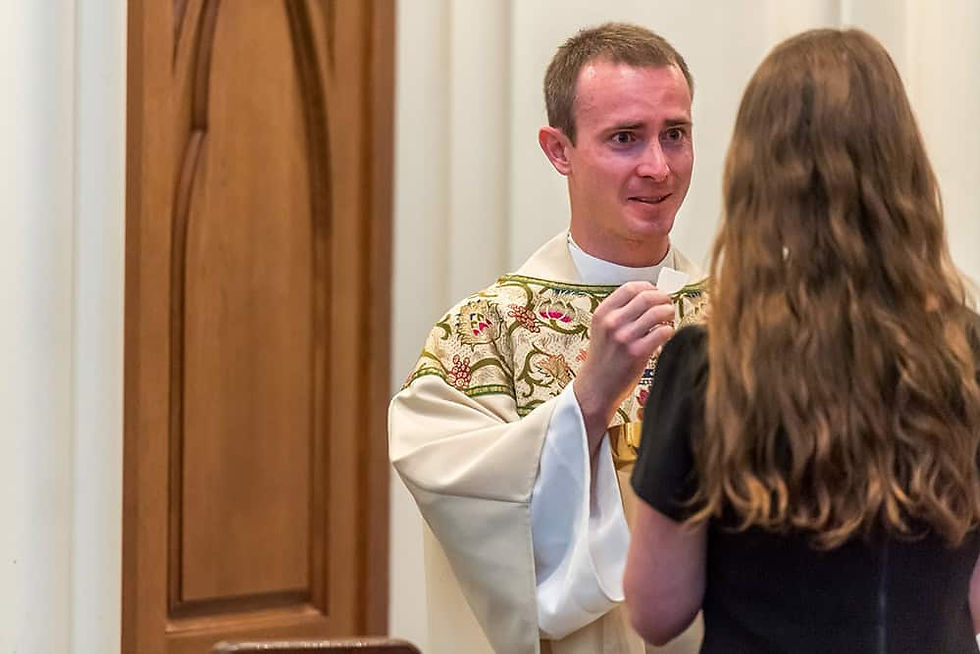 Father Chris Considine offering Holy Communion to a woman