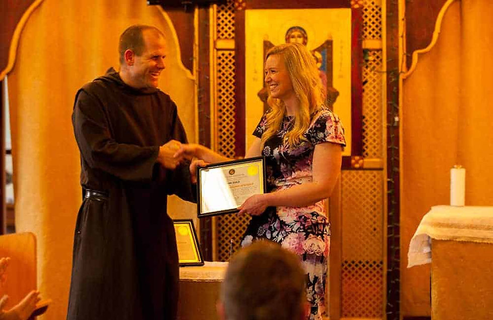 Father Nathan Cromley, president of the Saint John Institute, hands Brianne Schulze her diploma at the inaugural graduation ceremony for the institute April 15. (Photo by Andrew Wright)