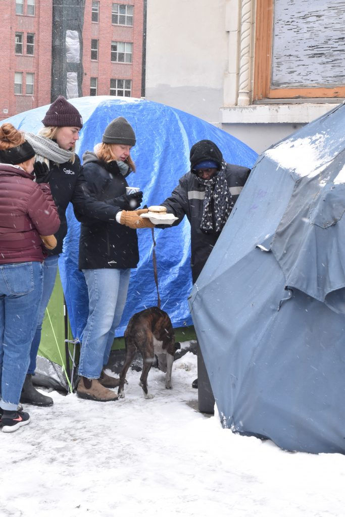 Christ in the City missionaries visit with some “friends on the street” at their camp. Missionaries walk certain routes multiple times per week in the hopes of forming concrete, consistent friendships. (Photo courtesy of Christ in the City)