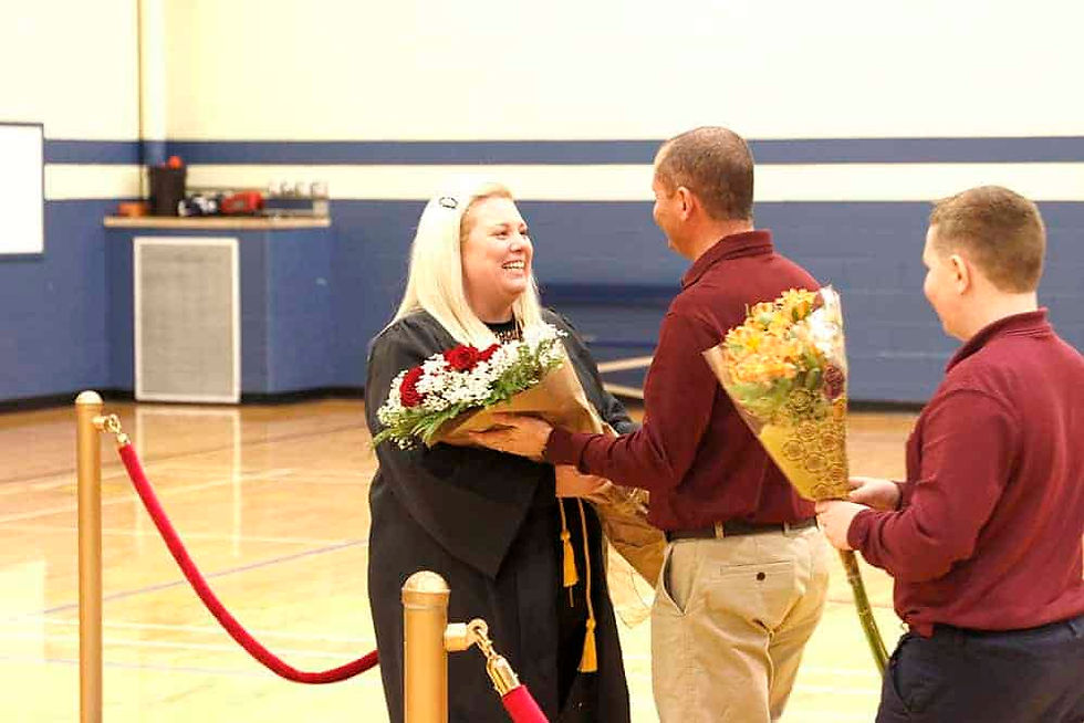 Kemmery Hill receives flowers from her husband during a surprise graduation ceremony at St. John the Baptist in Longmont Dec. 6 celebrating Hill earning her doctorate of education. (Photos by Aaron Lambert )