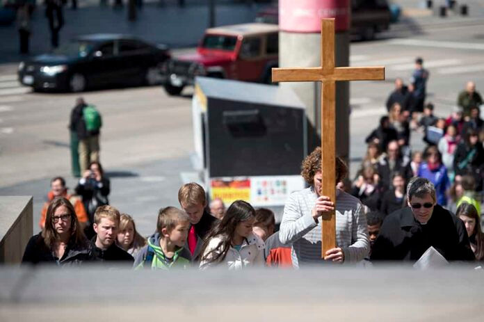 DENVER, CO - APRIL 3: Cross bearer Matthew Gear (C-R)leads a group of the faithful including Fr. Michael Carvill (R) up the stairs at the RTD bus stop near Broadway and Colfax Avenue during a Way of the Cross March on Good Friday on April 3, 2015 in Denver, Colorado. (Photo by Daniel Petty/Denver Catholic)