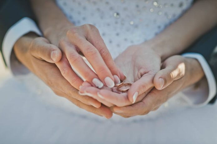 Mans and female hands hold wedding rings.