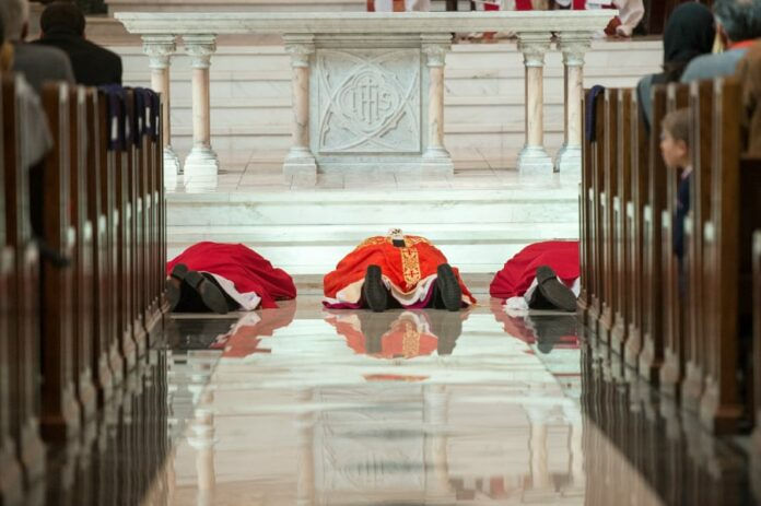 DENVER, CO - APRIL 3: Archbishop Samuel J. Aquila, center, prostrates himself along with other deacons during the beginning of the Celebration of the Lord's Passion on Good Friday at the Cathedral Basilica of the Immaculate Conception April 3, 2015 in Denver, Colorado. (Photo by Daniel Petty/Denver Catholic)