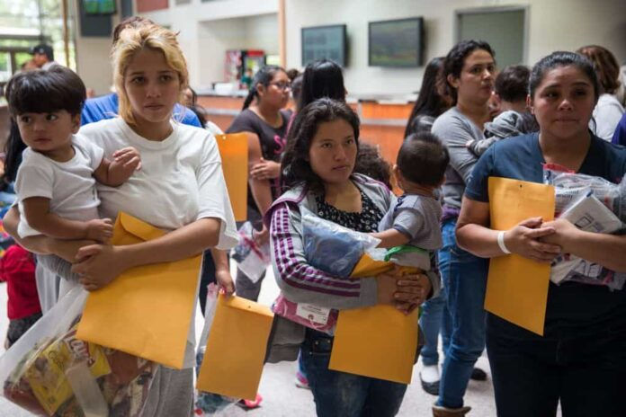 Immigrants wait to head to a nearby Catholic Charities relief center after being dropped off at a bus station shortly after release from detention through "catch and release" immigration policy on June 17, 2018 in McAllen, Texas. - "Catch and release" is a protocol under which people detained by US authorities as unlawful immigrants can be released while they wait for a hearing. (Photo by Loren ELLIOTT / AFP) (Photo credit should read LOREN ELLIOTT/AFP/Getty Images)