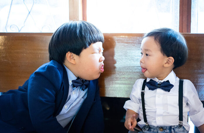 Naughty brothers make funny face, there are playing In the church with formal suit.