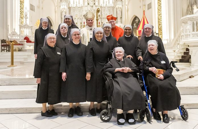 From L-R, first row: Sister Therese Marie, Sister Sarah, Denver Archbishop Samuel Aquila, Cardinal James Stafford. Second row: Sister Michael, Sister Juliana Sally, Mother Mercy, Sister Mary Sylvia. Lowest role: Sister Christine, Mother Provincial Julie Marie, Sister Joseph Marie, Sister Mary Augustine and Sister Emilie pose after a farewell Mass for the Little Sisters of the Poor at the Cathedral Basilica of the Immaculate Conception on October 25, 2022, in Denver, Colorado. The Little Sisters of the Poor are departing Denver after 105 years of service the Mullen Home for the Aged. (Photo by Daniel Petty/Denver Catholic)