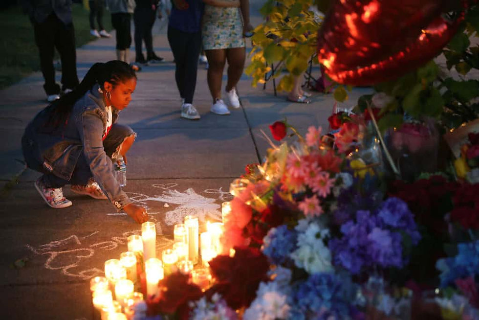 A woman chalks a message at a makeshift memorial outside of Tops market on May 15, 2022 in Buffalo, New York. A gunman opened fire at the store May 14 killing ten people and wounding another three. The attack was believed to be motivated by racial hatred. (Photo by Scott Olson/Getty Images)