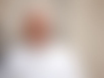Smiling pope in white papal robes and skullcap against a soft beige background, looking calm and warm