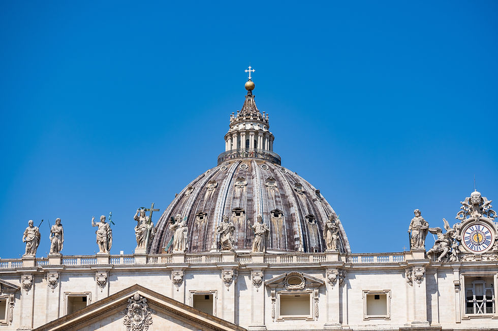 St. Peter’s Basilica dome and statues against a clear blue sky, with a clock on the right and no people visible.