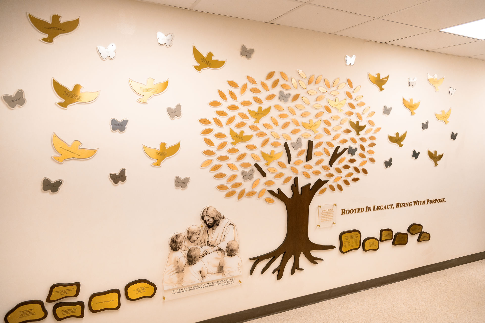 Wall mural of a tree with gold leaves, doves and butterflies, plus Jesus with children; text: Rooted in Legacy, Rising With Purpose.