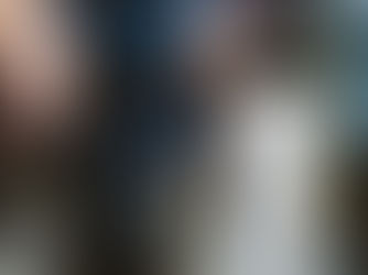 Close-up of a person holding rosary beads and a paper during an outdoor prayer gathering, with others blurred in background.
