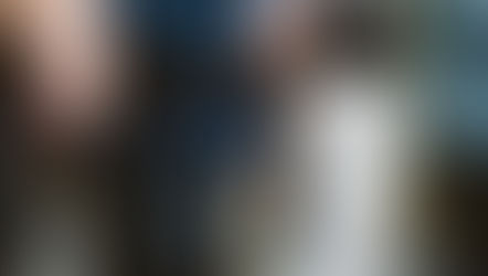 Close-up of a person holding rosary beads and a paper during an outdoor prayer gathering, with others blurred in background.